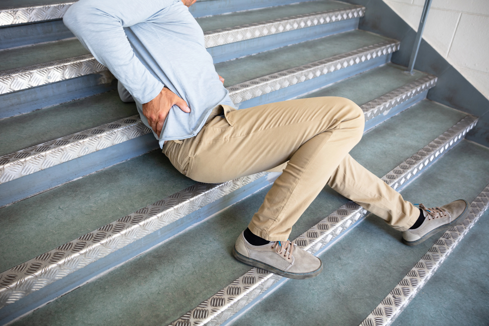 A man lying on a set of stairs after a slip and fall accident, which might settle out of court.